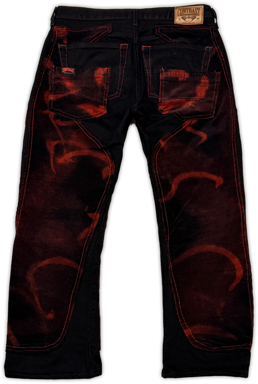 Black denim jeans with red flame-like distressed patterns and red contrast stitching, shown from the back on a white background.