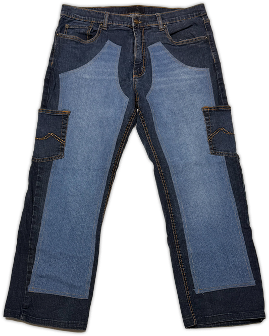 A pair of blue denim jeans with a unique patchwork design, featuring large light blue panels on the front thighs and dark blue panels on the sides and legs, shown against a plain white background.