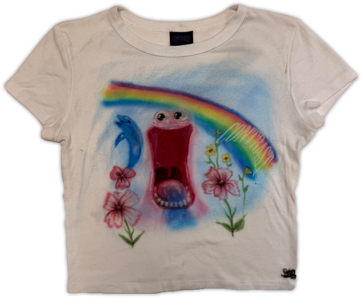 A white-colored short-sleeve t-shirt featuring a colorful spray-painted graphic of a smiling open mouth, a blue dolphin, pink flowers, and a rainbow on the front.