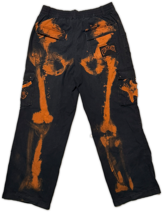Black cargo pants with a distressed orange bone print and a 'contrast' patch on the back pocket, shown flat on a white background.