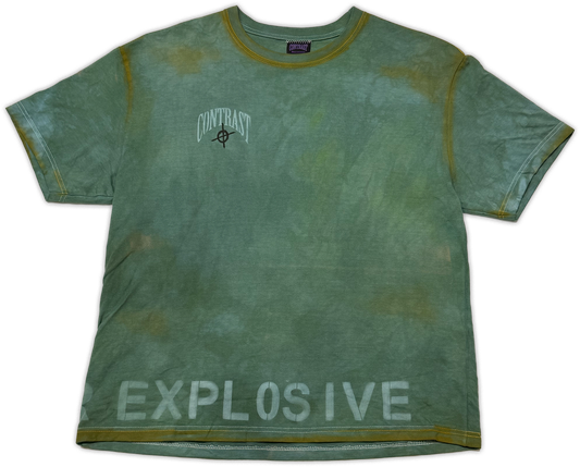 A short-sleeve crewneck t-shirt in a distressed sage green color with yellow-green trim on the collar and sleeve cuffs. The shirt features a white 'CONTRAST' logo with a target symbol on the left chest and 'EXPLOSIVE' printed in white across the bottom hem.