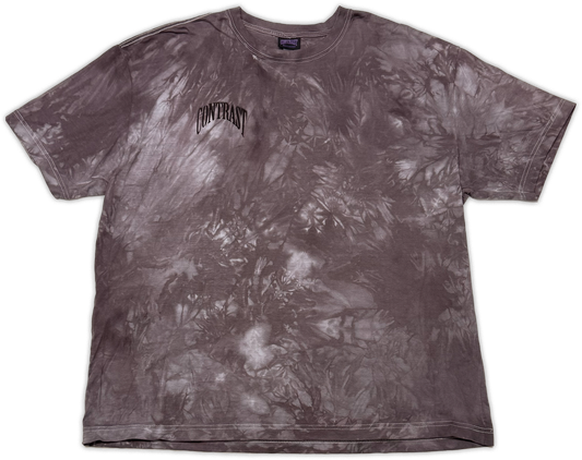 A short-sleeve crewneck t-shirt featuring a dark gray and white tie-dye pattern, with the word 'CONTRAST' printed in a stylized black font on the left chest.