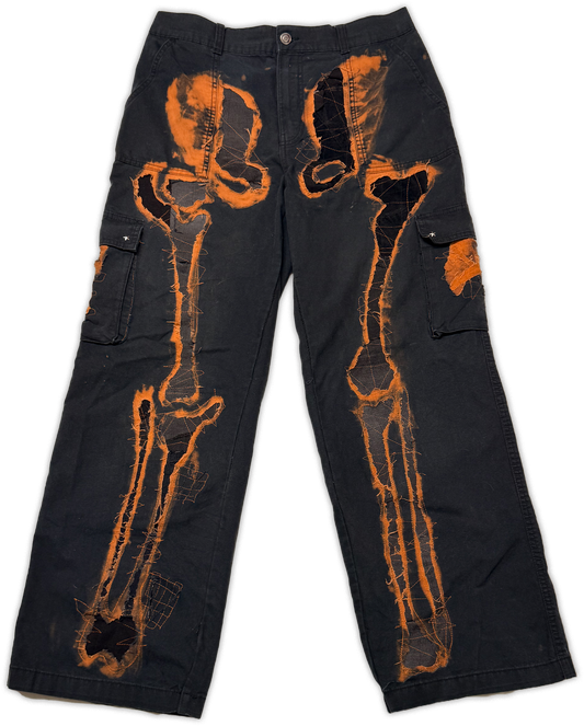 Black cargo pants featuring a prominent orange bone x-ray style graphic printed across the front, displayed flat against a white background.