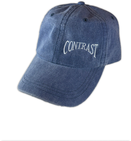 A blue denim baseball cap with the word 'CONTRAST' embroidered in white script on the front, shown against a plain white background.
