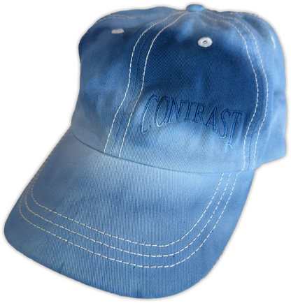 A light blue baseball cap with white contrast stitching and 'CONTRAST' embroidered in blue on the front, shown against a plain white background.