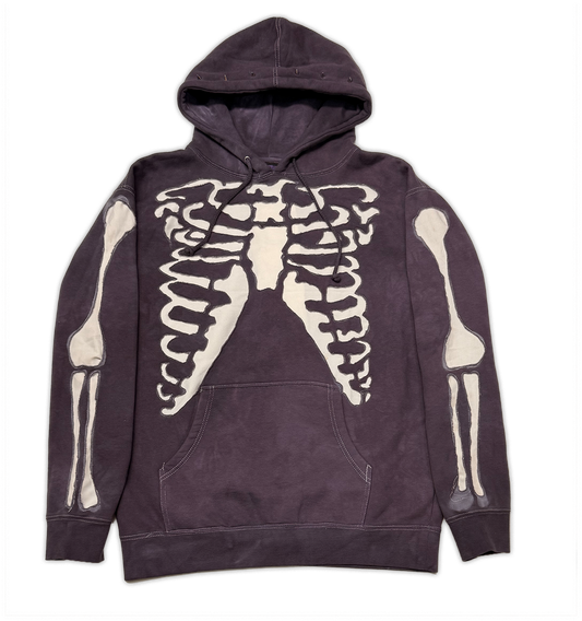 A dark plum-purple hooded sweatshirt featuring a large cream-colored rib cage graphic on the chest and matching skeletal arm and leg prints on both sleeves, displayed flat against a white background.