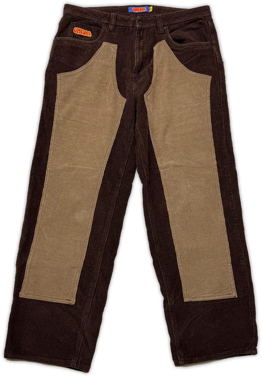 A pair of vintage work pants featuring dark brown corduroy sides and large tan canvas panel inserts on the front, photographed flat against a white background.