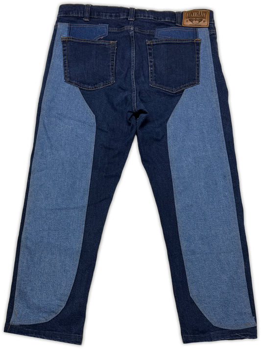 Back view of a pair of denim jeans with a distinctive color-blocked design featuring dark blue and medium blue panels, shown on a white background.