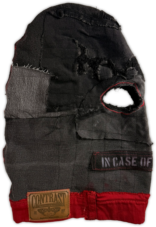 A distressed black balaclava mask with a red stitched eye opening, featuring a 'CONTRAST' brand patch on the lower left and an 'IN CASE OF' patch on the lower right, set against a plain white background.