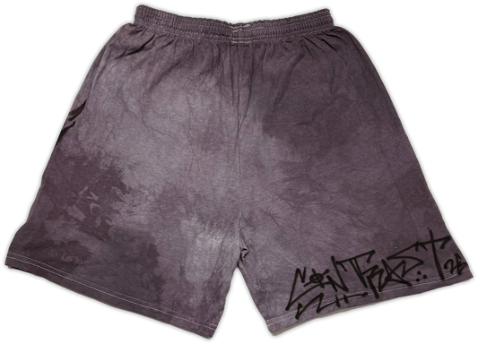 A pair of faded dark gray athletic shorts with a black graffiti-style “contrast” graphic on the lower right leg, displayed flat against a white background.