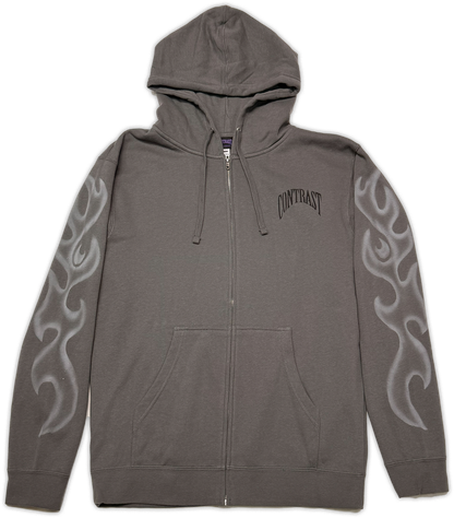 A dark gray zip-up hoodie with a front kangaroo pocket, featuring a black arched 'CONTRAST' logo on the left chest and white flame graphics printed down both sleeves.