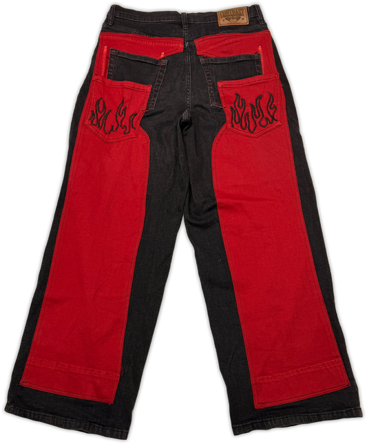 Red and black denim pants with flame embroidery on the back pockets, shown flat against a white background.